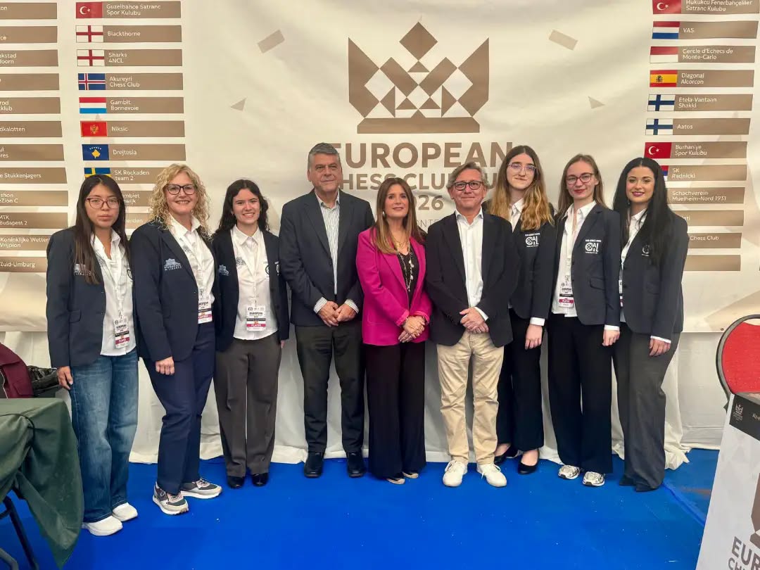 Un grupo de nueve personas posa sobre una alfombra azul ante un cartel de European Chess Club Cup.