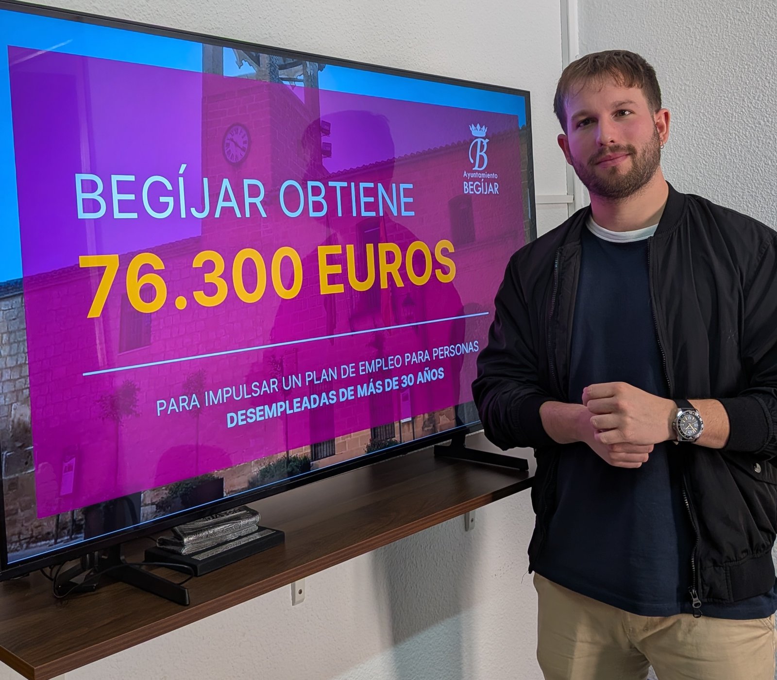Un hombre de pie junto a una pantalla grande que muestra el texto Begíjar obtiene 76.300 euros para un plan de empleo.