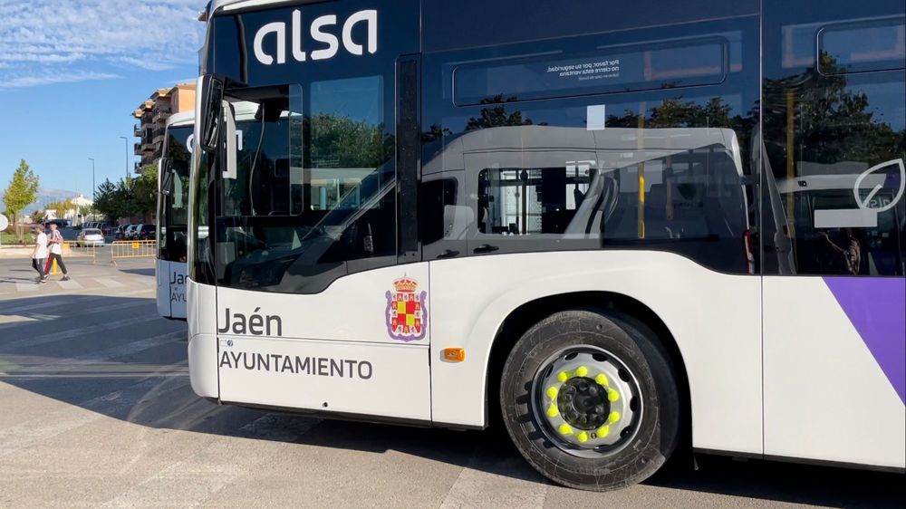 Autobús blanco de Alsa con el rótulo Jaén Ayuntamiento y escudo, junto a otro autobús y personas al fondo.